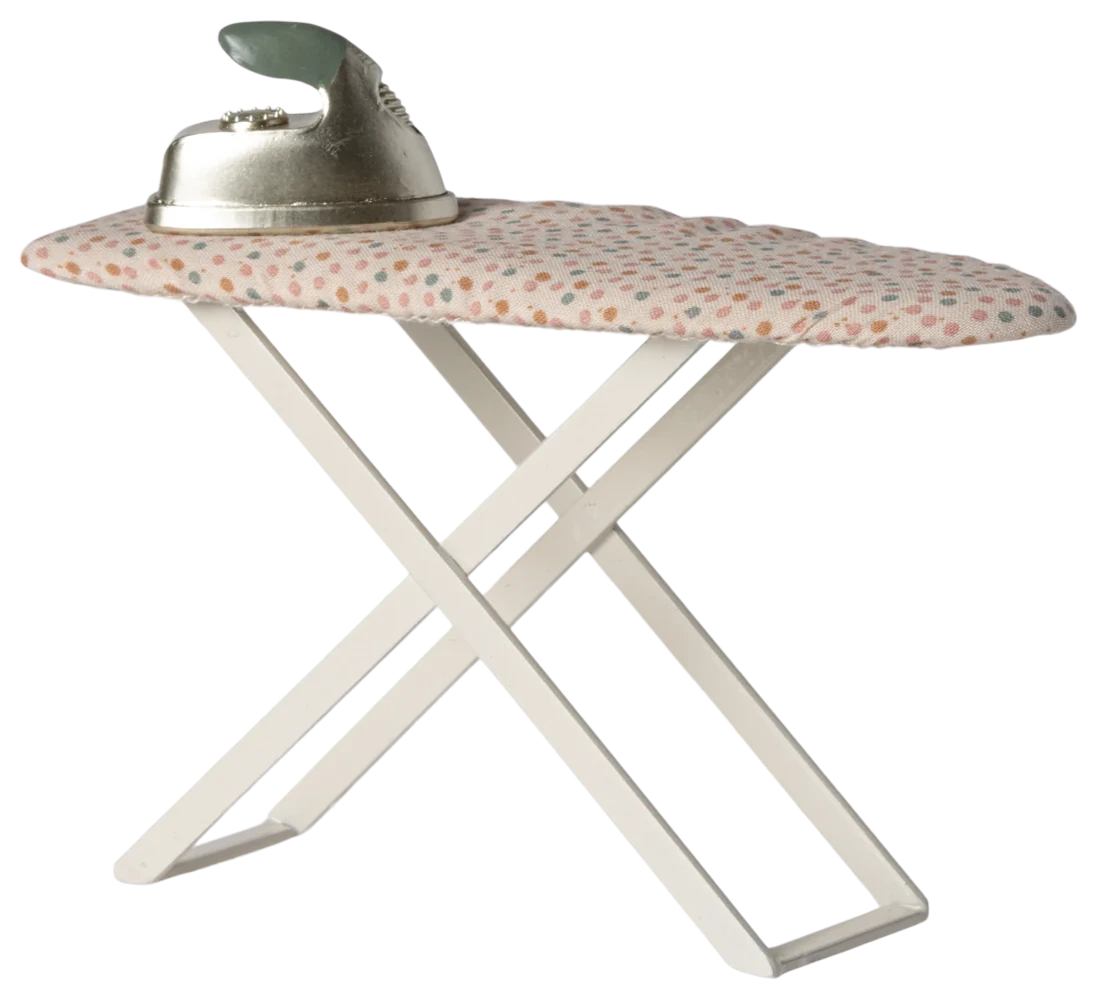 A toy iron with a polka dot pattern on the surface, designed for play, resting on a white ironing board.