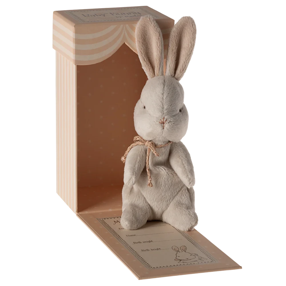 Plush rabbit toy with a bow tie in a wooden box on a white background