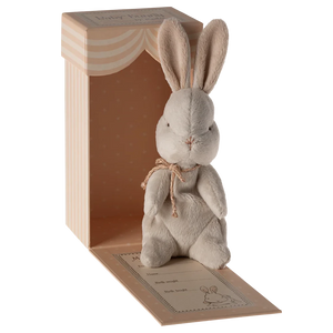 Plush rabbit toy with a bow tie in a wooden box on a white background