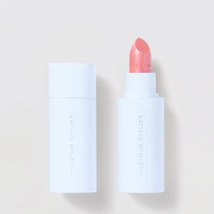 Lipstick with white casing and pink shade on a light beige background