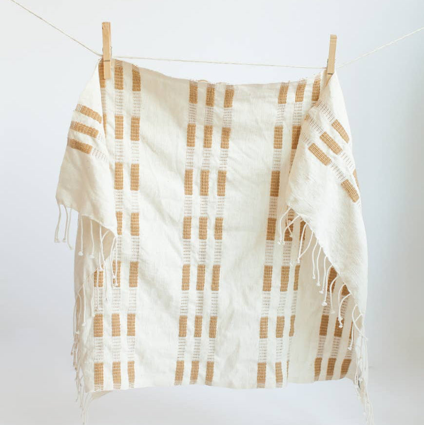 An ochre and white tea towel with a clothespin.