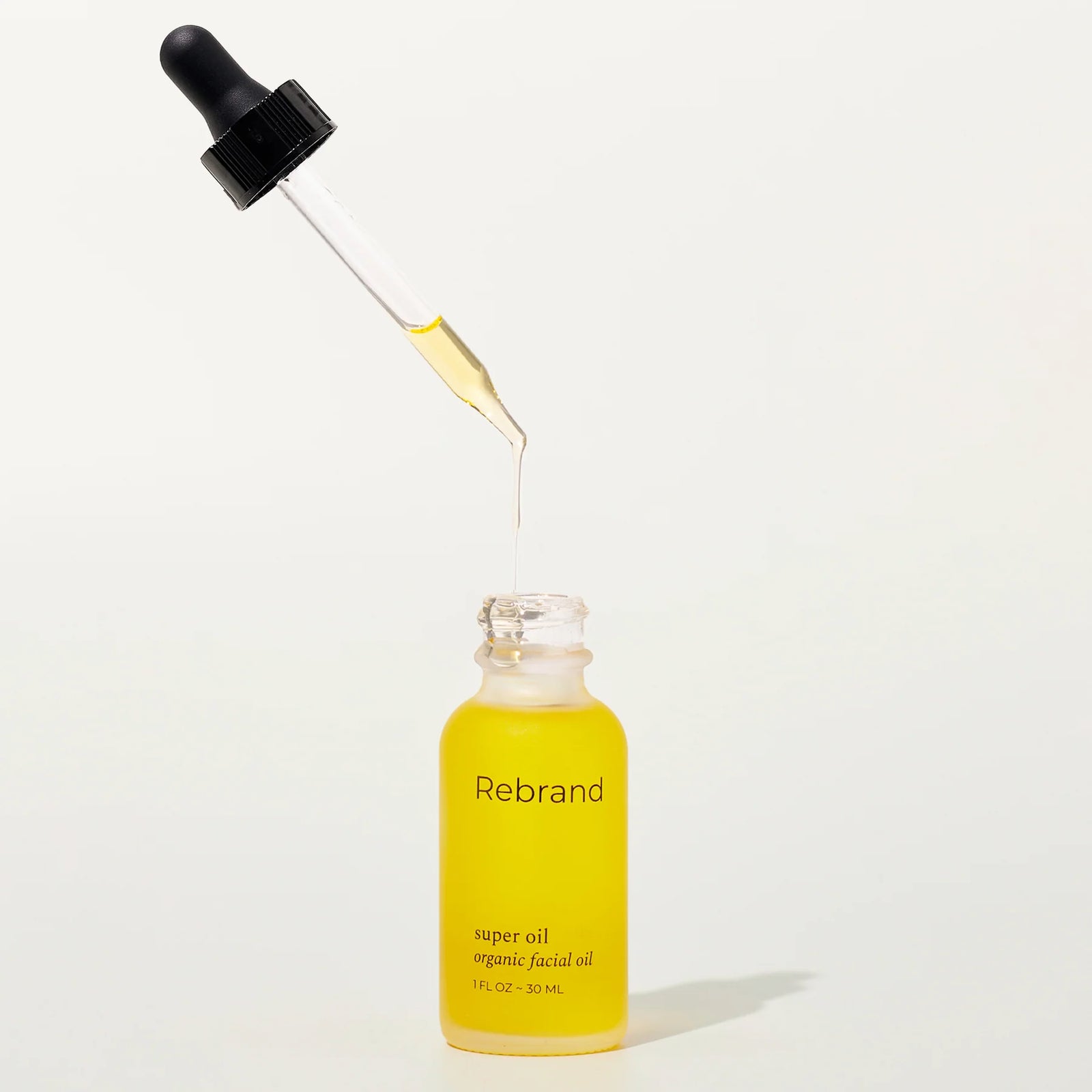 Yellow dropper bottle labeled 'Rebrand' on a white background