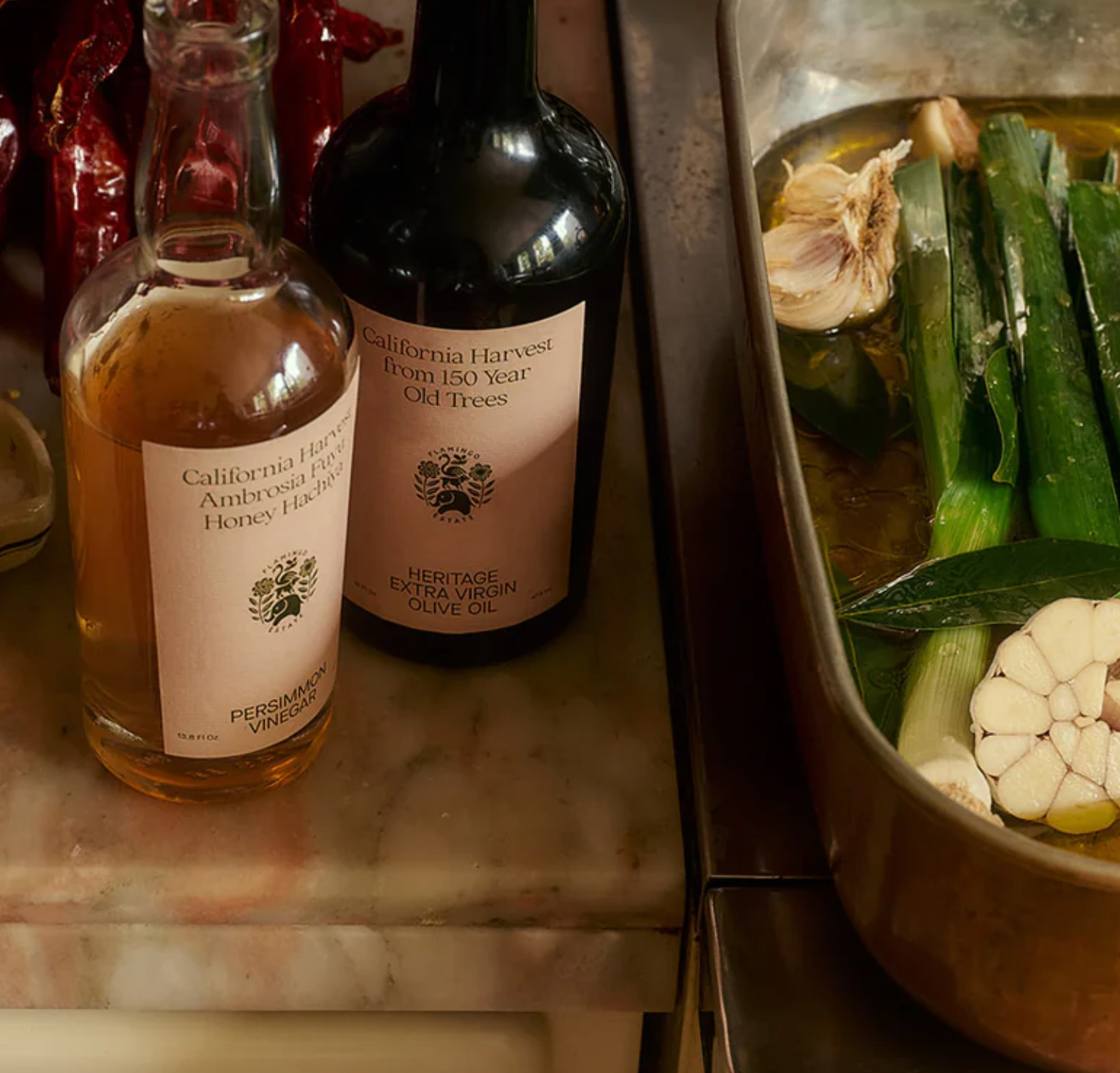 Oil and vinegar bottles next to a roasting pan with leeks. 