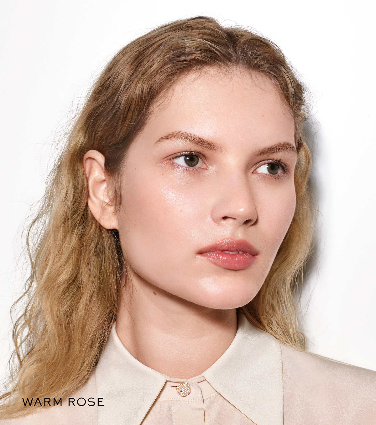Woman with blonde hair wearing a beige shirt on a white background