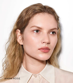 Woman with blonde hair wearing a beige shirt on a white background