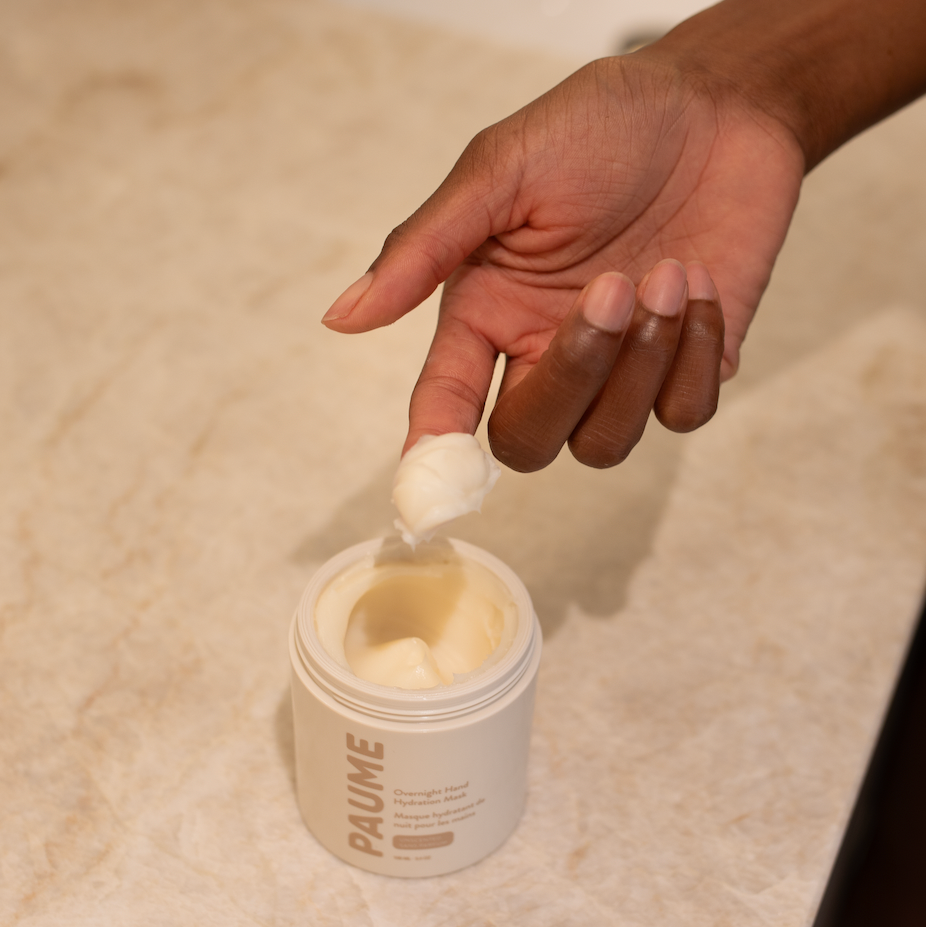 A person scooping out the Paume hand mask, with a counter in the background. 