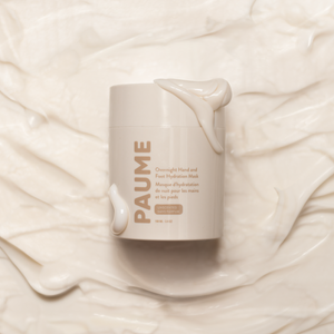 A container of Paume hand mask with product in the background. 