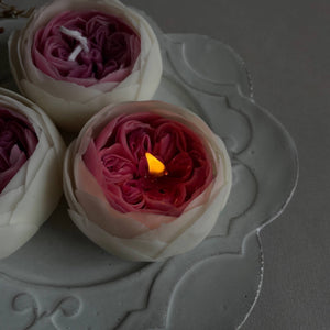 Peony candles on a white saucer. 
