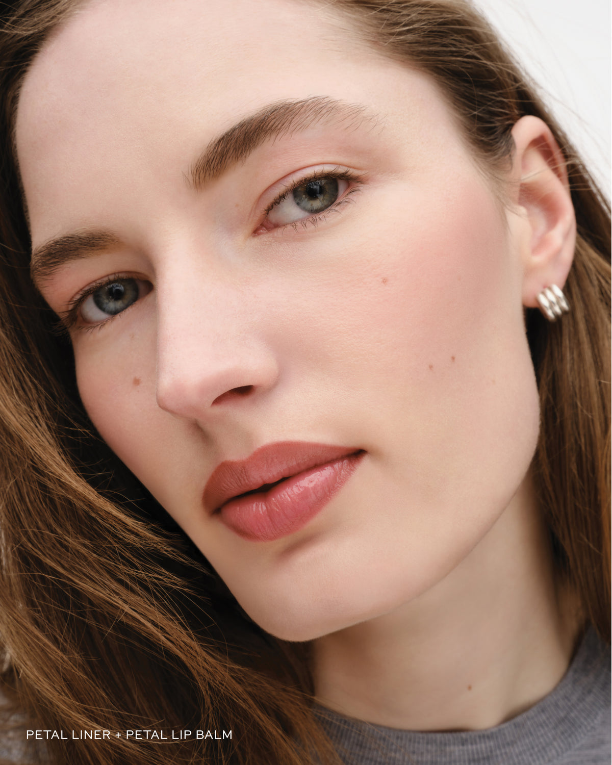 Close-up of a woman's face with a focus on her eye and lips, wearing earrings.