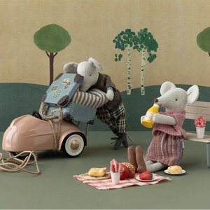 Toy scene with a toy car and toy mice in a picnic setting with trees in the background.