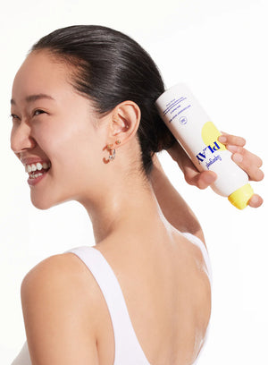 Woman holding a bottle of Supergoop PLAY behind her head