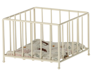 A small, beige-colored metal playpen with a cushion inside, designed for doll-sized figures.