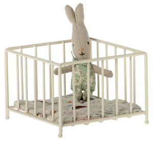 Stuffed rabbit toy in a small crib with a white background