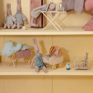Miniature toy setup with plush toys and accessories on a yellow shelf.