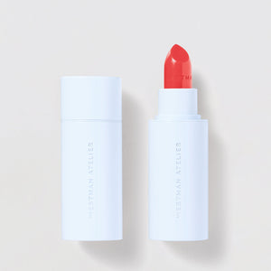 Lipstick with white casing and red shade on a light beige background