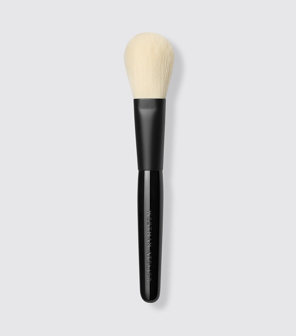 An oval-shaped powder brush with a black handle and beige bristles, designed for precise application of powder products.