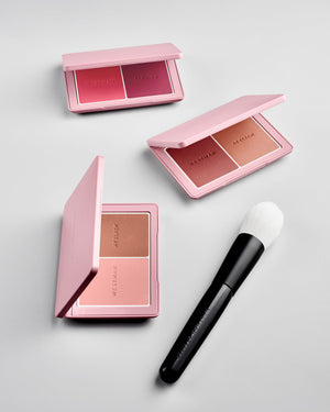 Makeup palette with blush shades and a brush on a light gray background