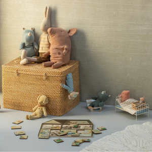 Wicker toy box with plush toys and children's furniture in a room.