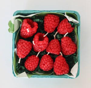 A set of raspberry candles, in a green paper produce box