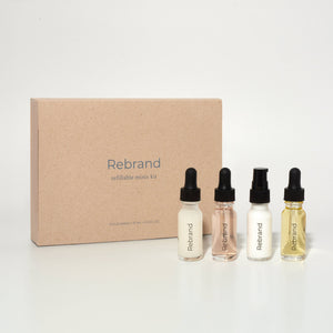 A collection of four 15 ML glass bottles with dropper caps, labeled Dream Cleanser, Power Serum, Day & Night Cream, and Super Oil, positioned in front of a brown cardboard box with the brand name Rebrand visible.