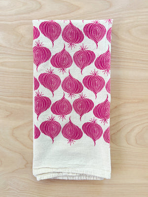 The Noon Designs red onion tea towel is white with bright red onions printed on it. 