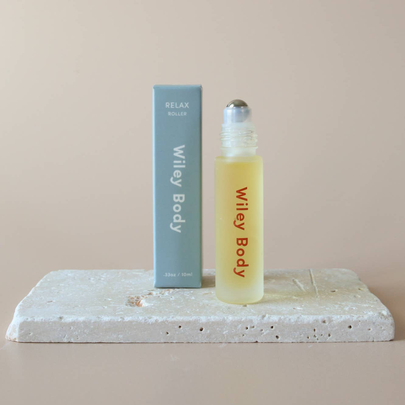 A small bottle of Wiley Body relax roller oil with a label that reads 'For my body', positioned on a textured surface.