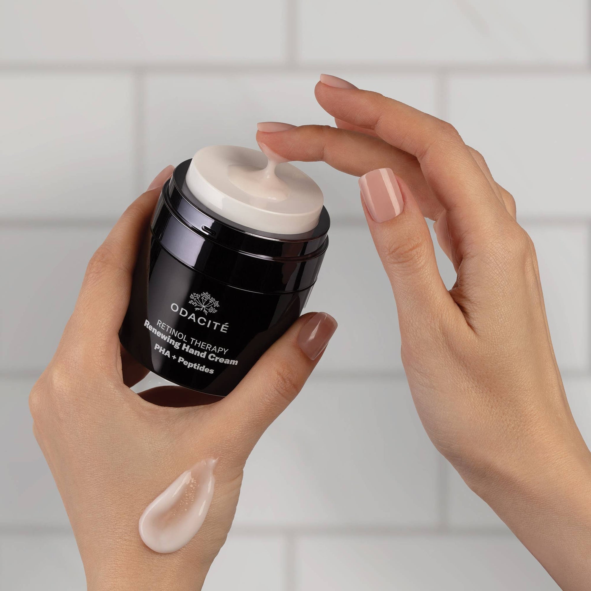 Person applying Odacite hand cream to their hand with a white background