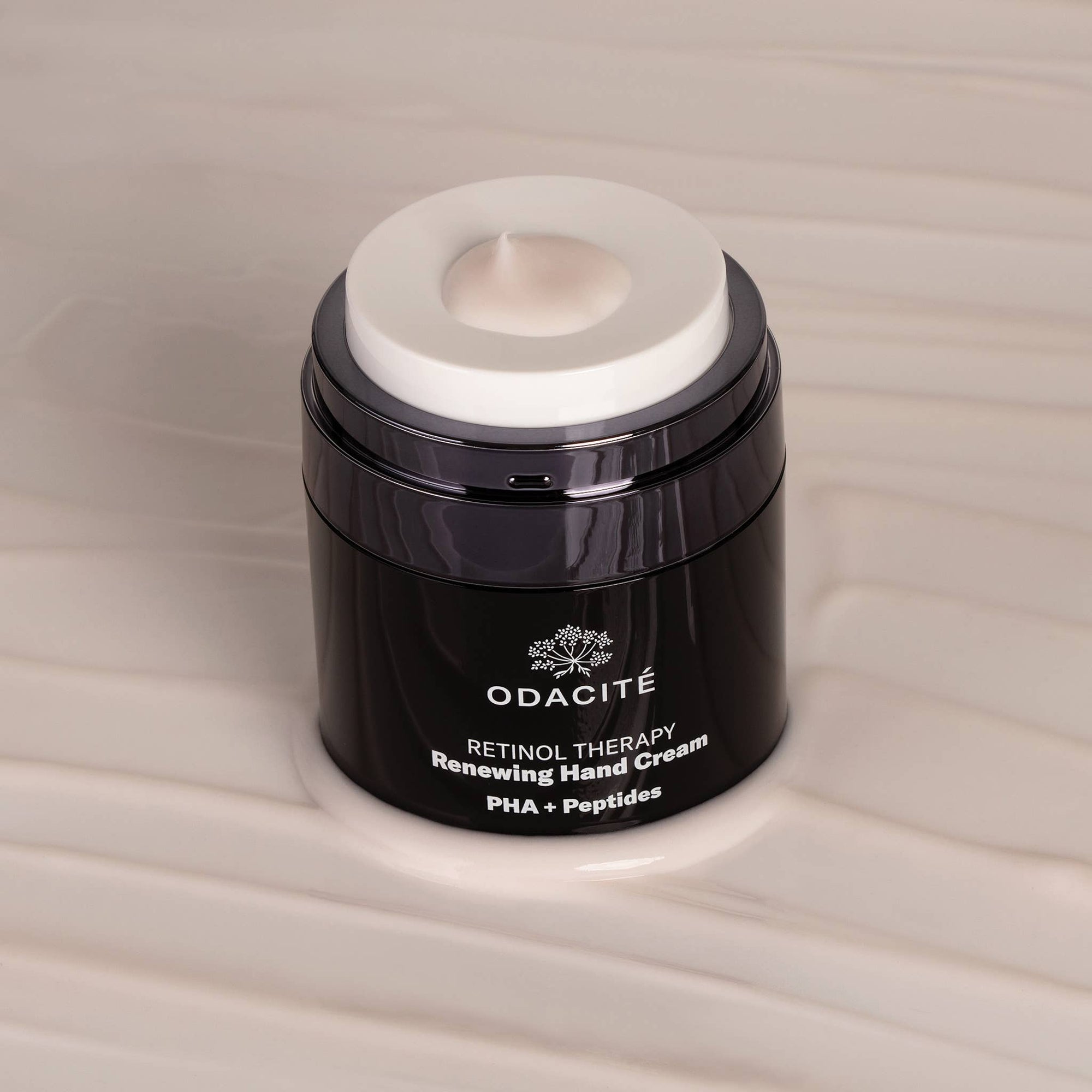 A black jar of Odacite Retinol Therapy Renewing Hand Cream on a white surface
