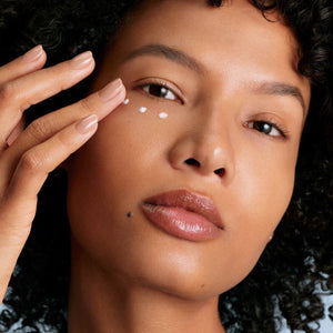 Close-up of a person applying cream to their face with a hand