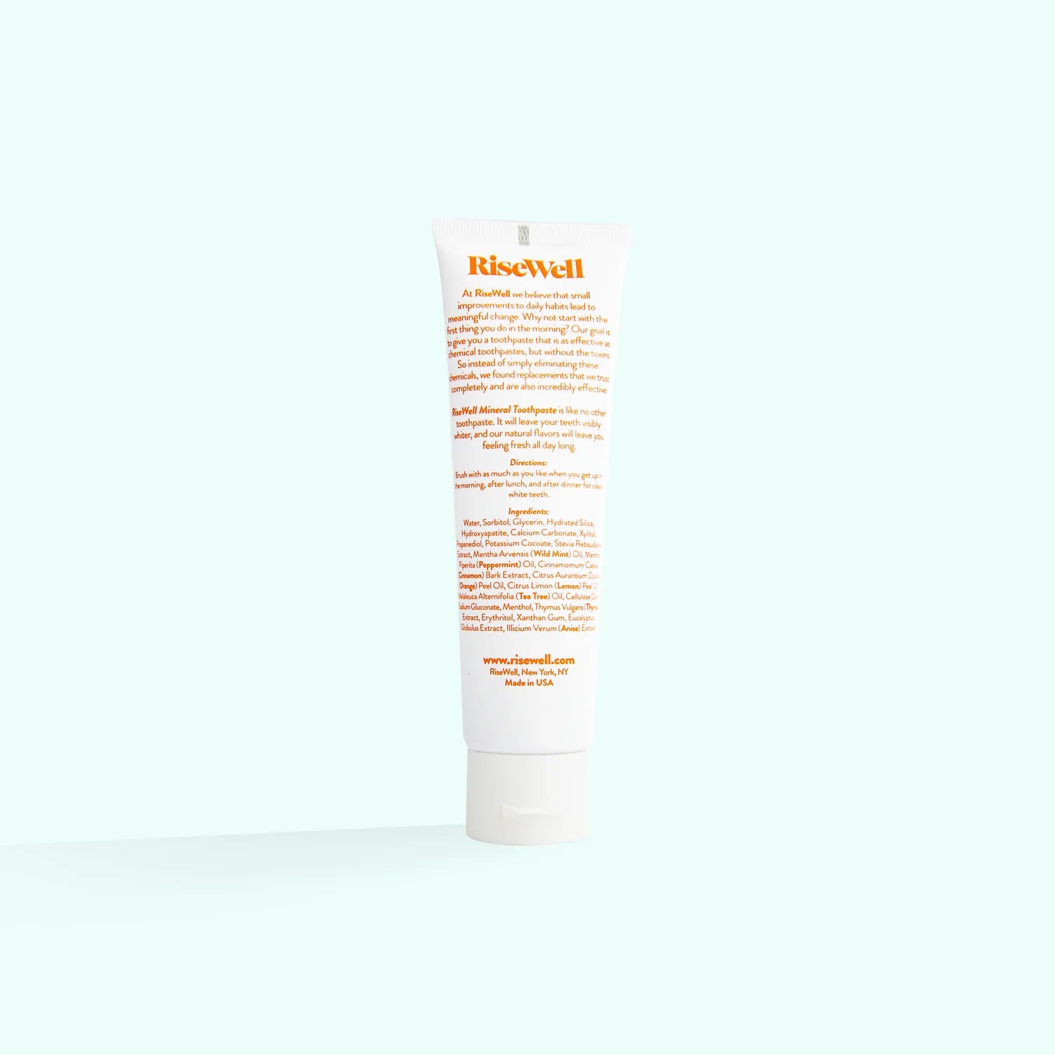 A tube of RiseWell Mineral Toothpaste with orange and white color scheme on a white background.