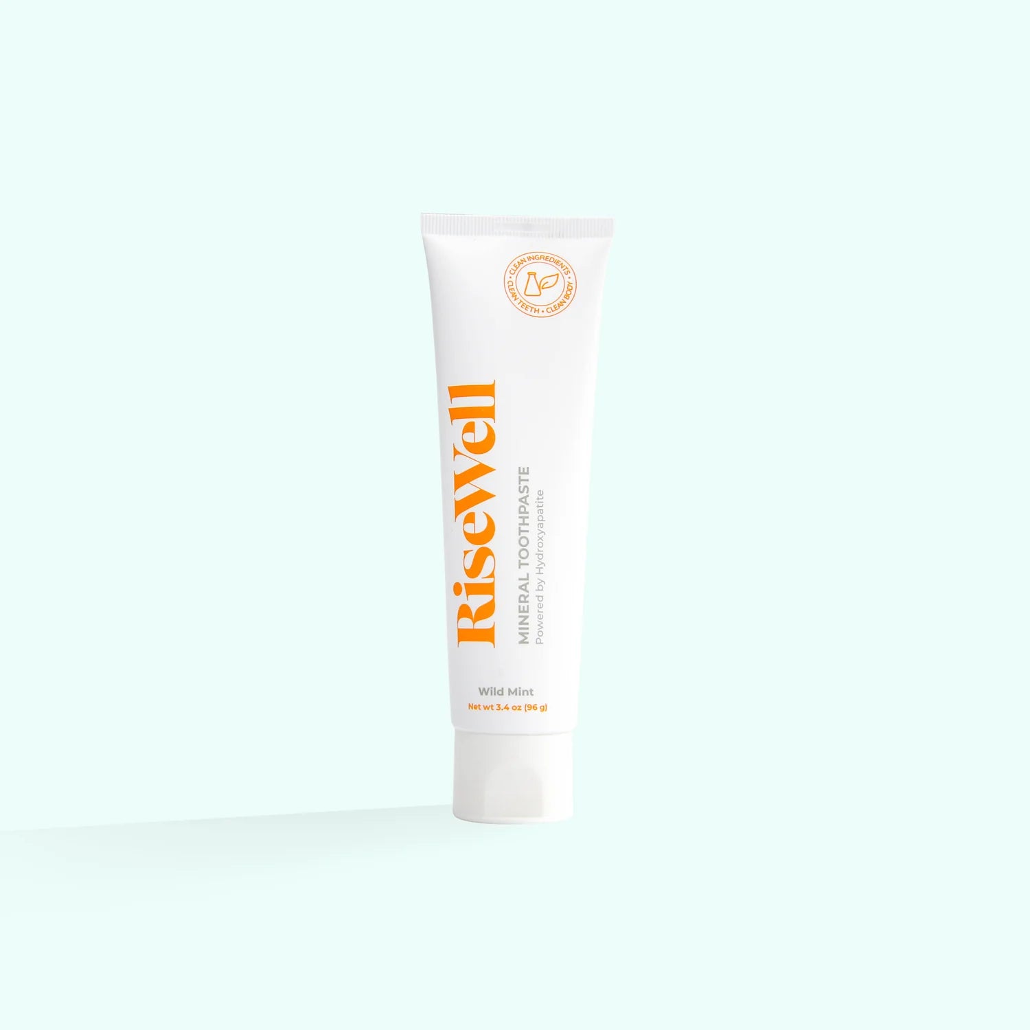 A tube of RiseWell Mineral Toothpaste with orange and white color scheme on a white background.