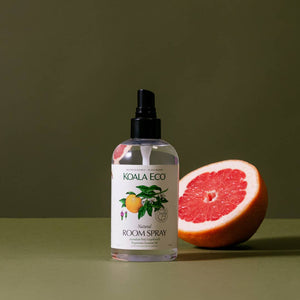 A bottle of the organic Koala Eco room spray, next to a pink grapefruit