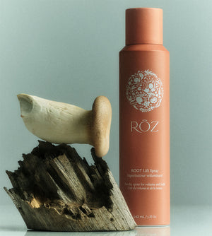 A bottle of ROZ Root Lift Spray, next to a piece of wood and a mushroom.