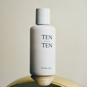 White bottle labeled 'TEN OVER TEN' on a reflective surface with a neutral background