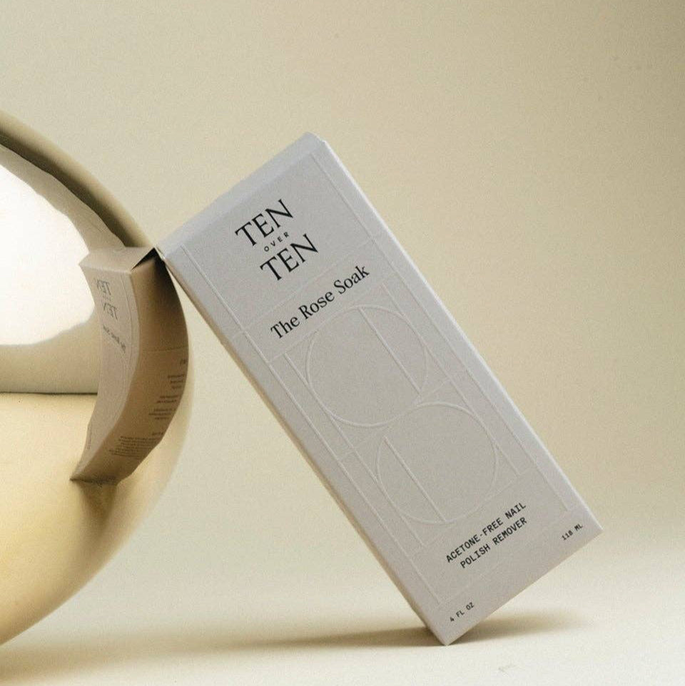White bottle labeled 'TEN OVER TEN' on a reflective surface with a neutral background