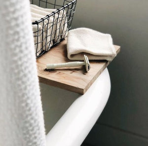 A white safety razor on the edge of a bathtub. 