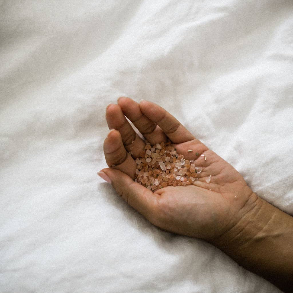 A person holding the rose bath salts in their hand. 