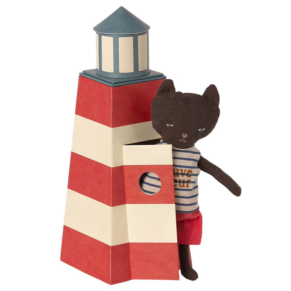 A toy cat figurine in a lifeguard outfit standing next to a striped lifeguard tower that is designed to look like a lighthouse.