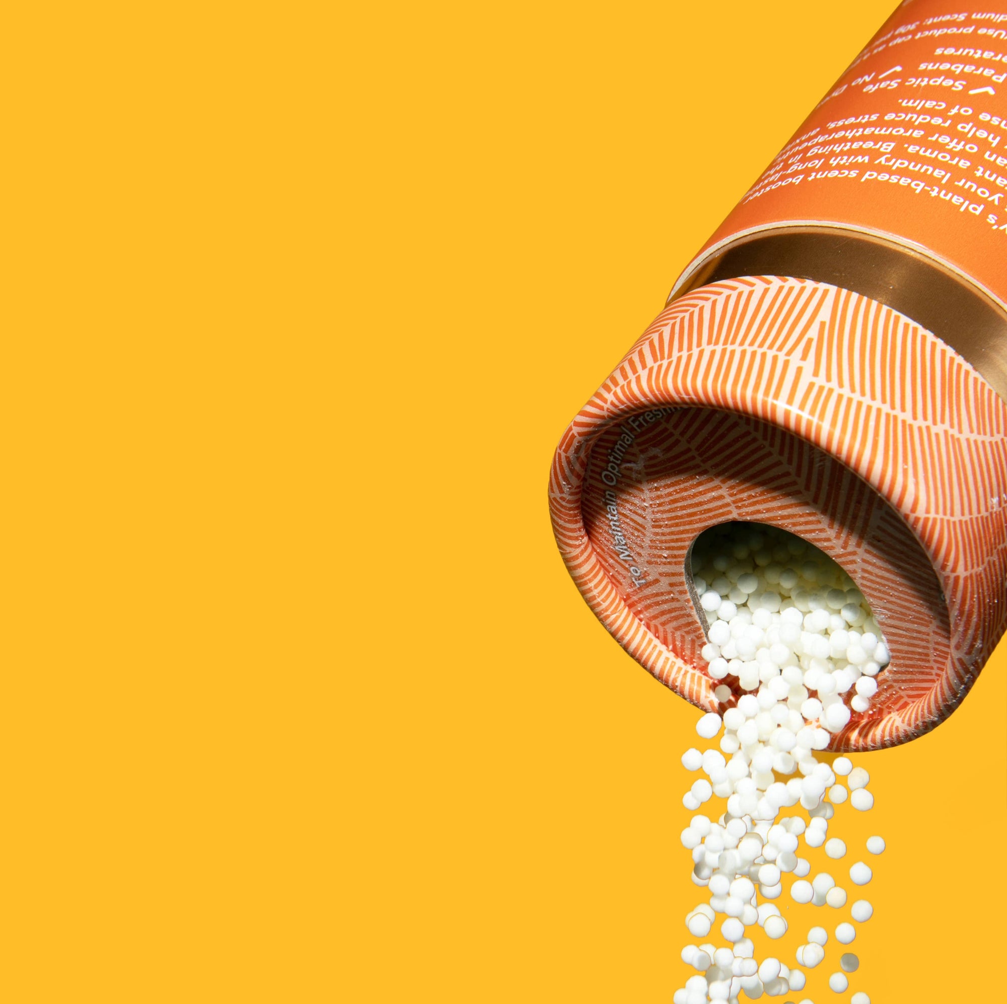 A bottle of Kind Laundry scent boosters on an orange background. 