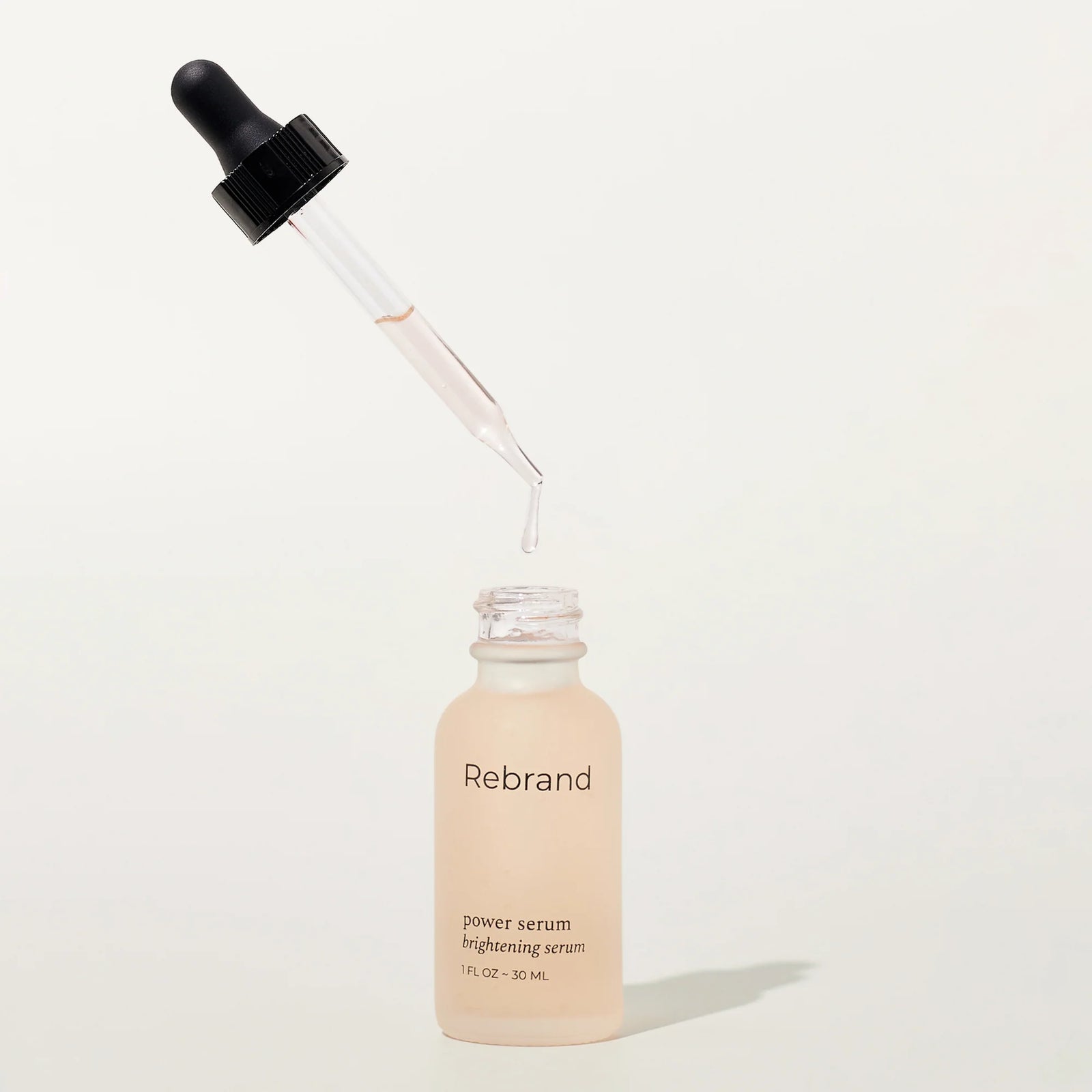 Skincare serum bottle with dropper labeled 'Rebrand' on a white background