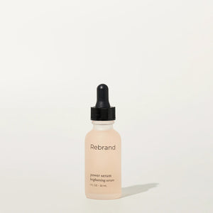 Skincare serum bottle labeled 'Rebrand' on a light beige background