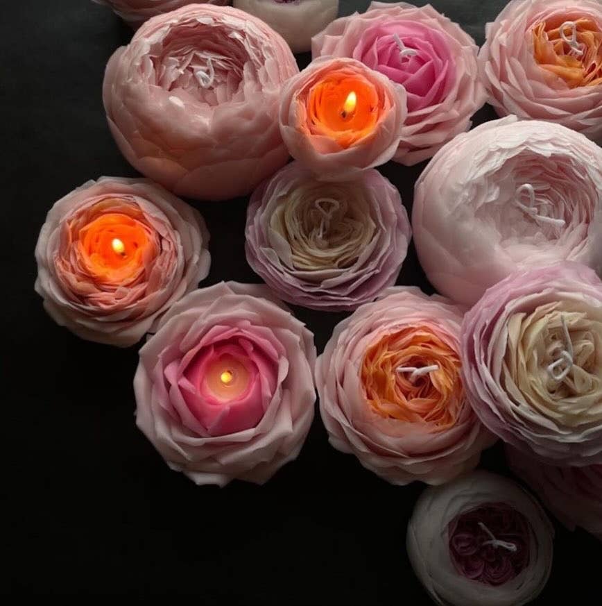 Decorative candles shaped like pink roses on a dark background