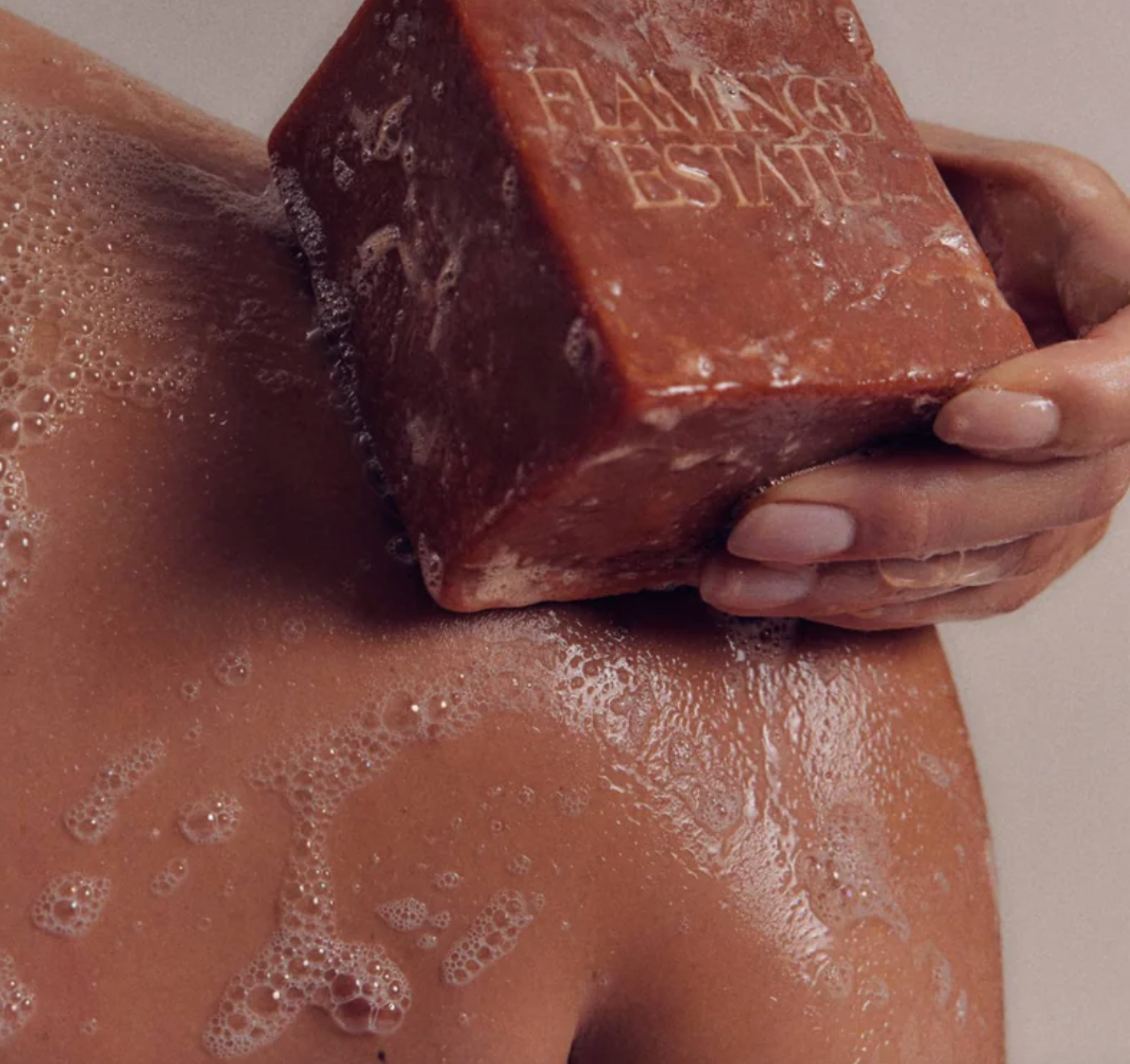 A person washes their body with a brick of soap. 