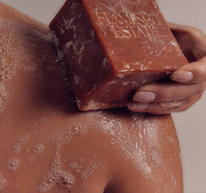 A person washes their body with a brick of soap. 
