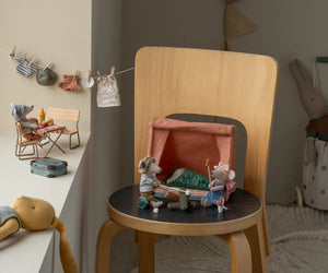Wooden chair with small toy figures and a miniature bed in a child's room.