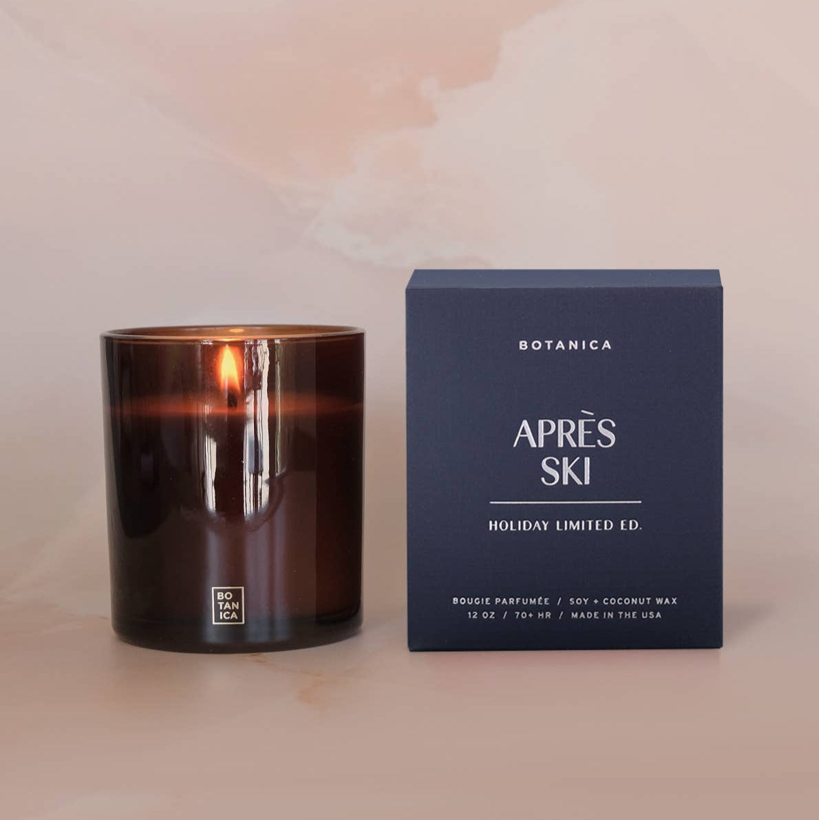 Candle and its packaging labeled 'Apres Ski' on a soft pink background