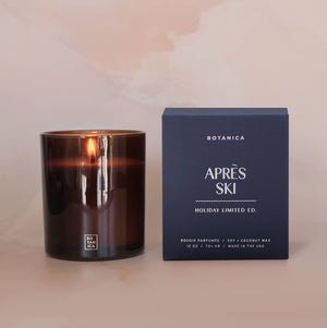 Candle and its packaging labeled 'Apres Ski' on a soft pink background