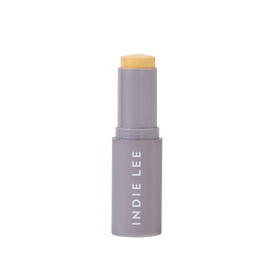 Cosmetic stick with beige cap and 'Indie Lee' branding on a white background