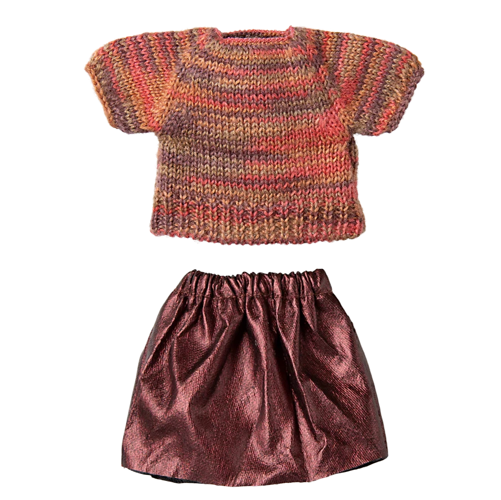 Knitted sweater and metallic skirt set on a white background