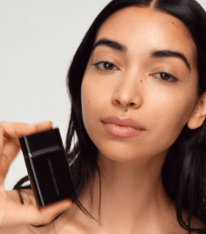 A woman applying liquid super loaded makeup to her face